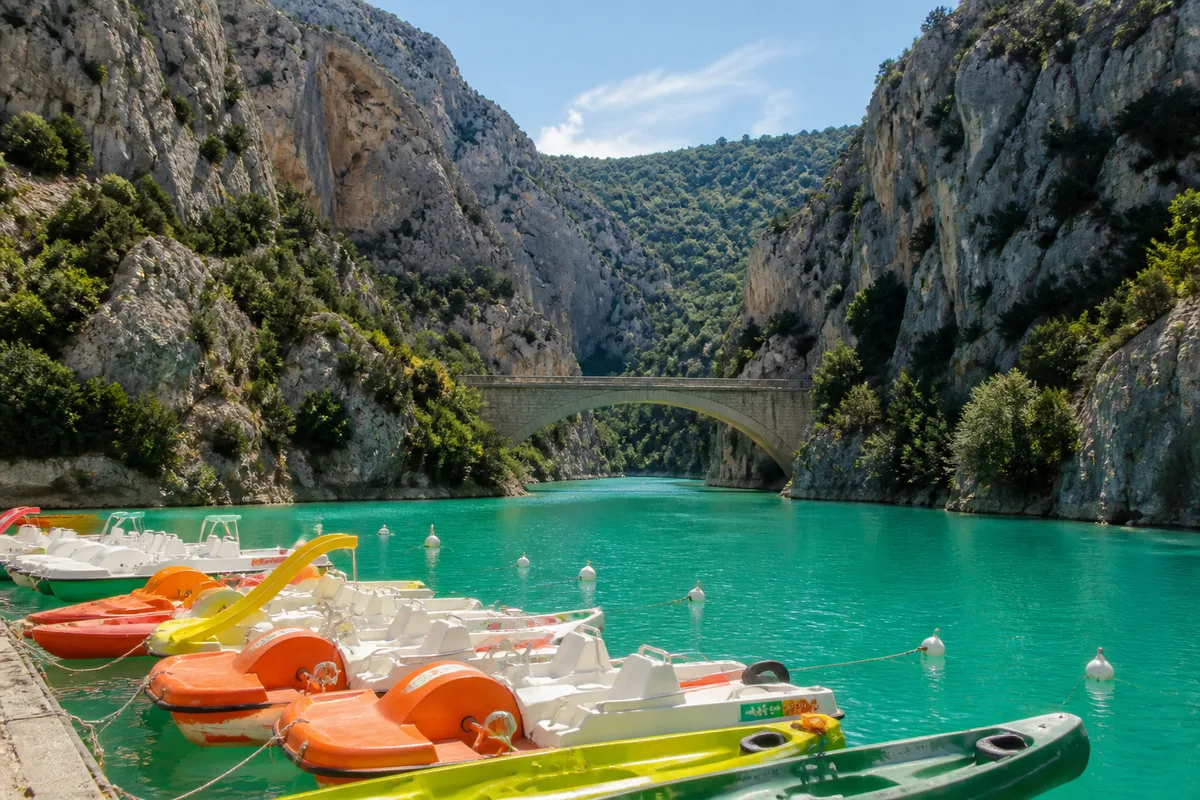 Petits bateaux électriques et canoës amarrés près de l entrée du canyon sous un pont de pierre